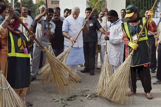 Indian Prime Minister Narendra Modi sweeps a road with a broom along with civic workers in New Delhi, India, Oct. 2, 2014. Mr. Modi vowed to clean up India’s streets. Associated Press