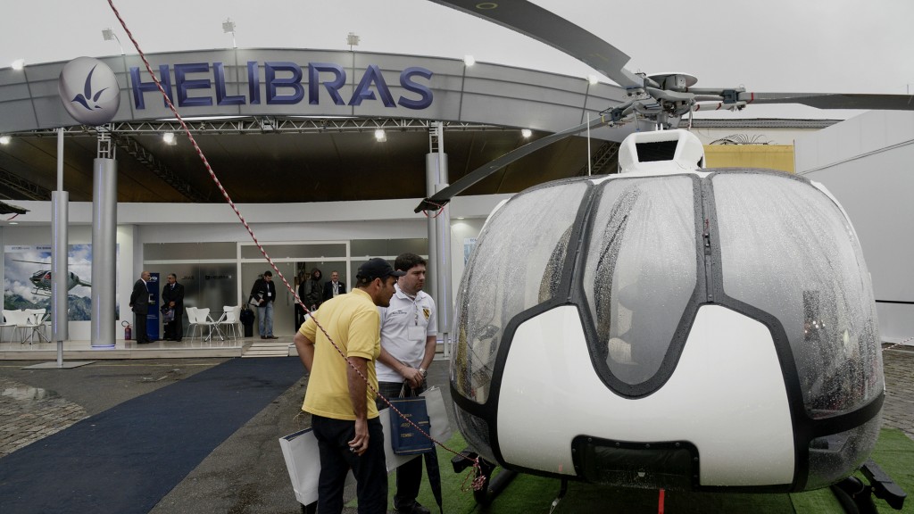 Visitors look at a helicopter made by Helicopteros do Brasil SA (Helibras) during the Latin American Business Aviation Conference & Exhibition (LABACE) in Sao Paulo, Brazil, on Wednesday, Aug. 13, 2014. A rebound in sales of business jets that began with the biggest, longest-range planes is spreading to small- and mid-size models as Embraer SA puts its newest aircraft into service. Photographer: Paulo Fridman/Bloomberg