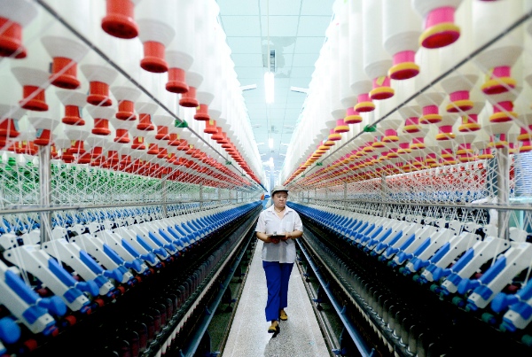A labourer works at a spinning mill in Xiajin County, east China’s Shandong Province, June 12, 2014 [Xinhua]