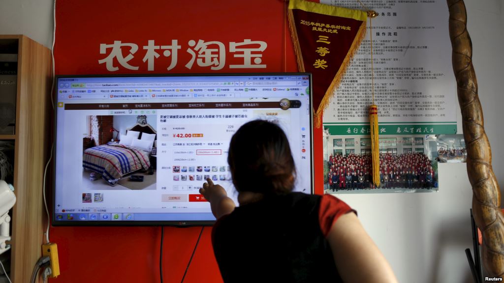 A customer points at a screen displaying a website of Alibaba's Taobao at a rural service center in Yuzhao Village, Tonglu, Zhejiang province, China, July 20, 2015. © Reuters
