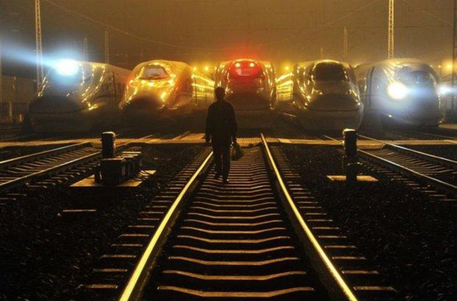 A railway worker walks in front of bullet trains at Hefei, China, built like many railways around the world entirely by Chinese labour with Chinese supervision. (Reuters photo)