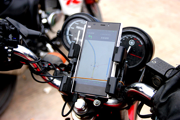 A motorcyclist uses a mobile phone navigational system to map out his route. Companies, such as Amap.com and Baidu.com, have developed Beidou-based navigational applications for smartphone users. [Photo provided to China Daily]