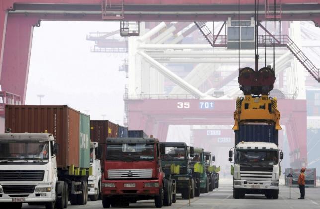 A crane lifts a shipping container from a truck to load it onto a ship at a port in Qingdao, Shandong province, China, October 13, 2015. REUTERS/Stringer