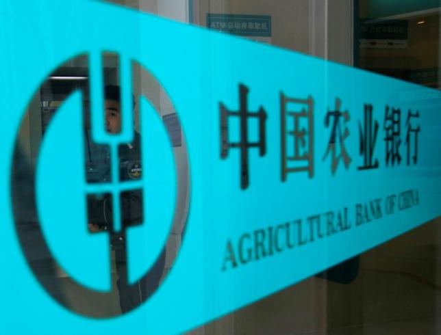 A security guard is seen through a logo of Agricultural Bank of China in Beijing April 23, 2013. REUTERS/Kim Kyung-Hoon