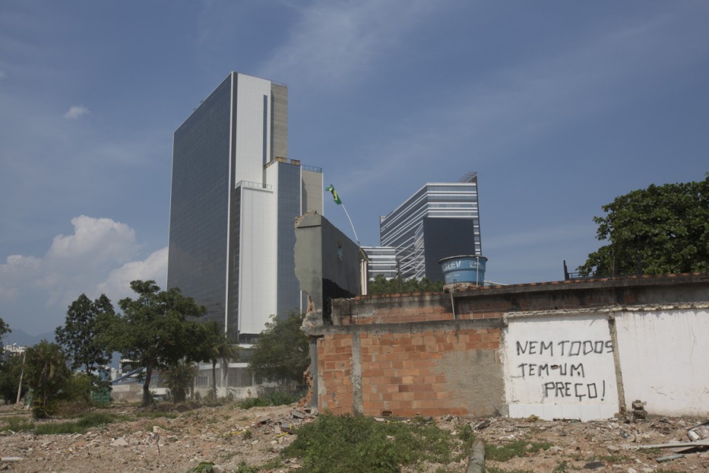 A demolished house with a sign that reads "Not everybody has a price" stands in front of the Olympic Media Center building, at the Vila Autodromo slum, in Rio de Janeiro, Brazil, Wednesday, March 9, 2016. Vila Autodromo has now been largely destroyed to make way for an access route into the Olympic Park. (AP Photo/Silvia Izquierdo)